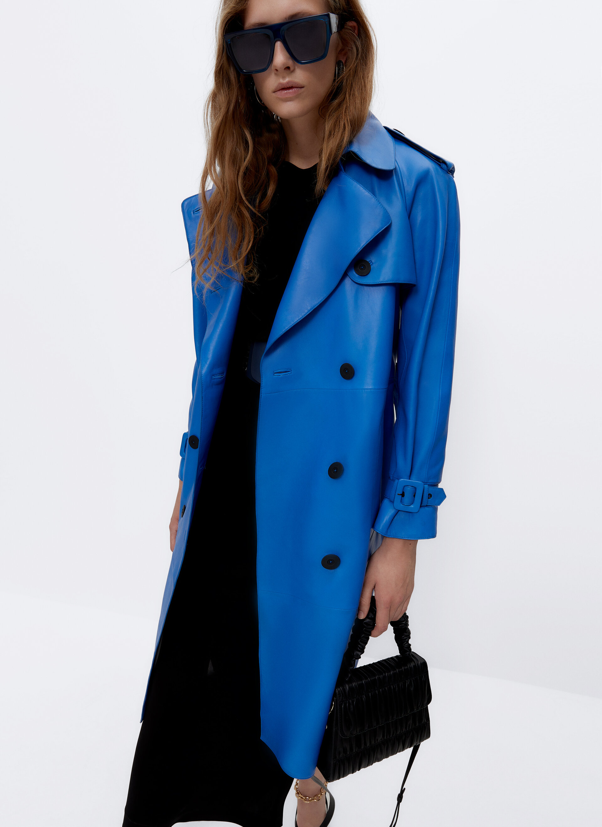 This amazing Uterque Blue Leather Trench Coat is a forever piece with a twist. It comes with classic trench styling and contrast black buttons and buckled cuffs and shoulders. 